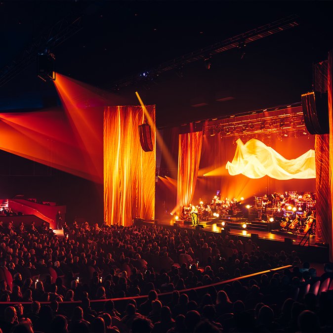 A duo performing live on a theatre stage.