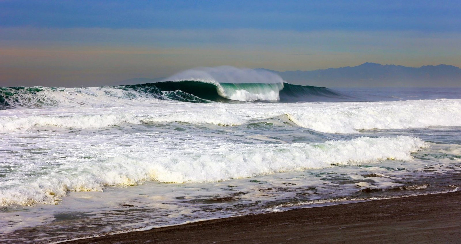 Waves breaking on the Southern California coast, where high surf and flood advisories are in effect.
